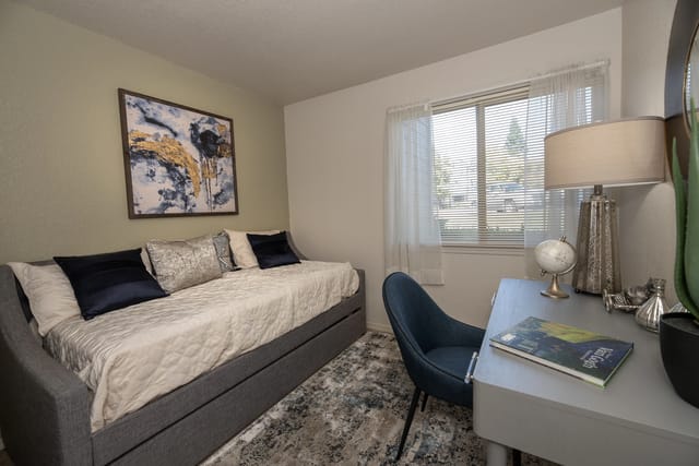 Cozy bedroom with a daybed, desk, and abstract wall art.