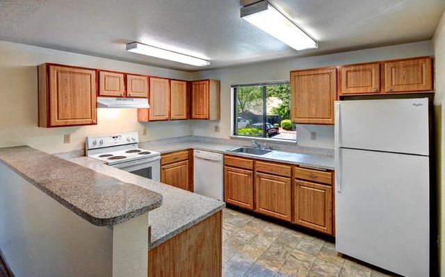 Kitchen with wooden cabinets, white appliances, and granite countertops.