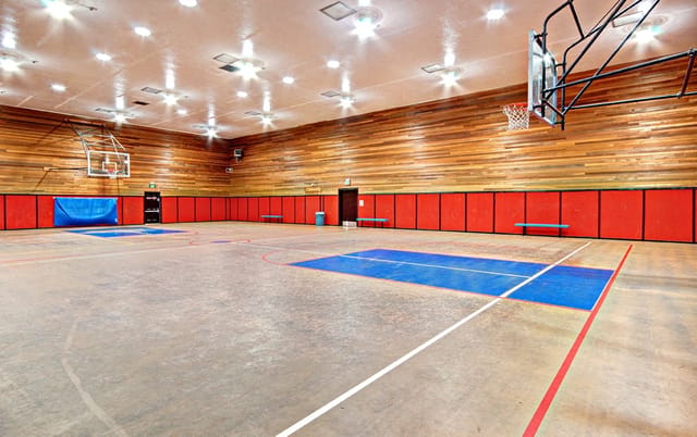 Basketball court with wood-paneled walls and red padding.