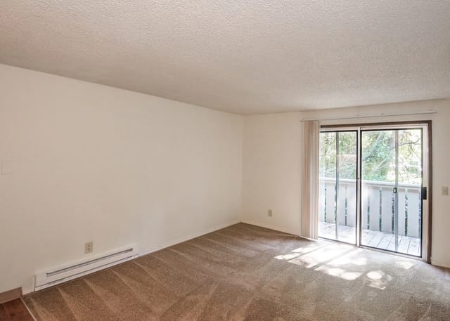 Living room with carpet, beige walls, and sliding glass door to a balcony.