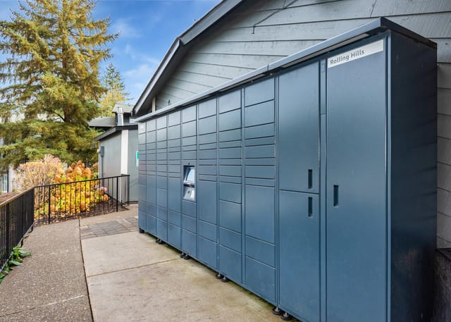 Exterior walkway with a long row of blue mail lockers beside the building.
