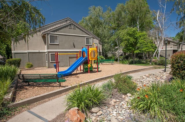 Playground at a multifamily property with a blue slide and colorful equipment.
