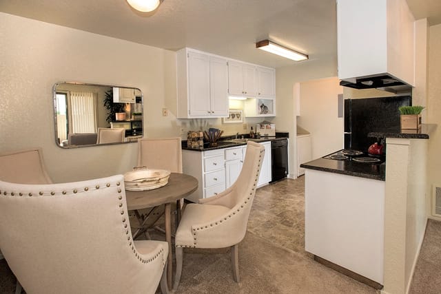 Dining area and kitchen with white cabinets and black appliances.