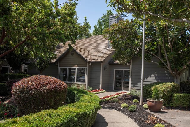 Exterior of apartment building with trees and landscaping.