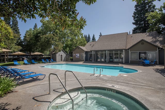 Swimming pool and hot tub area with lounge chairs and umbrellas.