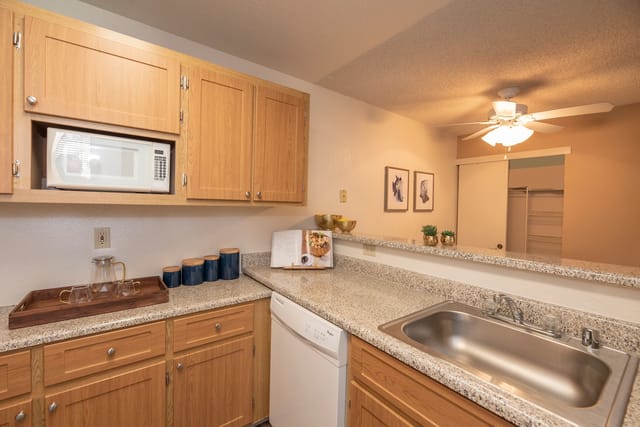 Kitchen with oak cabinets, built-in microwave, granite countertops, and a double sink.