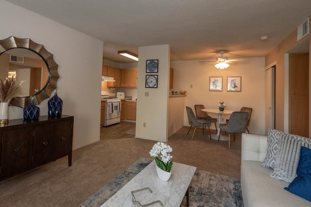 Living room and dining area of an apartment with a visible kitchen.