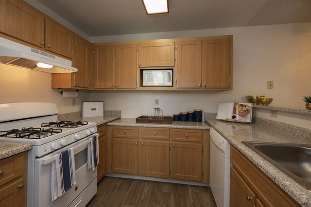 Kitchen with light wood cabinets, white appliances, and granite countertops.