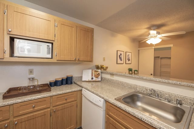 Kitchen with light wood cabinets, granite countertops, and a stainless steel sink.