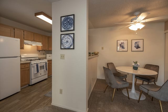 Kitchen and dining area with a white refrigerator, gas stove, and a dining table with four chairs.