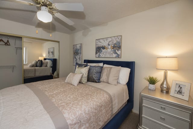 Bedroom with a king-size bed, mirrored closet, and ceiling fan.