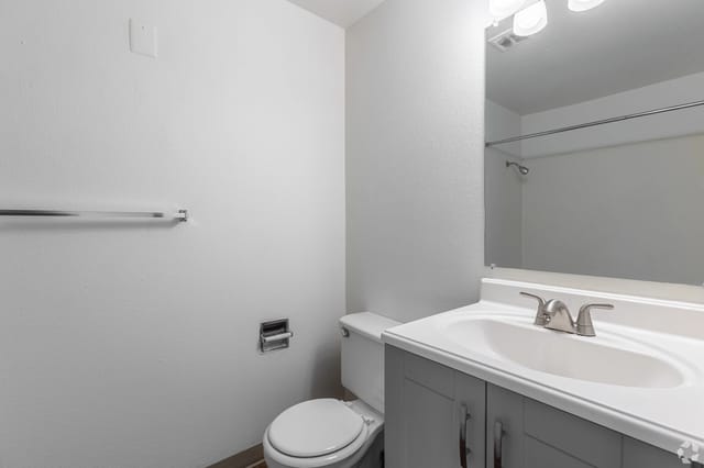 Bathroom with vanity sink, mirror, toilet, and towel bar.