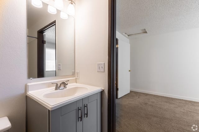 Bathroom vanity with sink, faucet, mirror, and overhead lights.