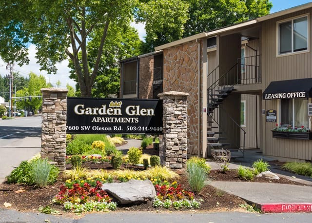Exterior of Garden Glen Apartments entrance with sign and landscaped garden.
