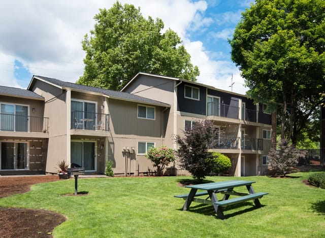 Exterior view of a multi-unit apartment building with balconies around a grassy courtyard.
