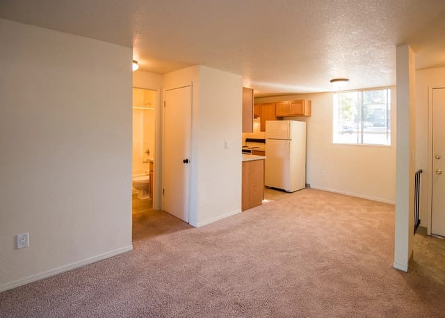 Interior view of a living room and kitchen area, with a glimpse of a bathroom.