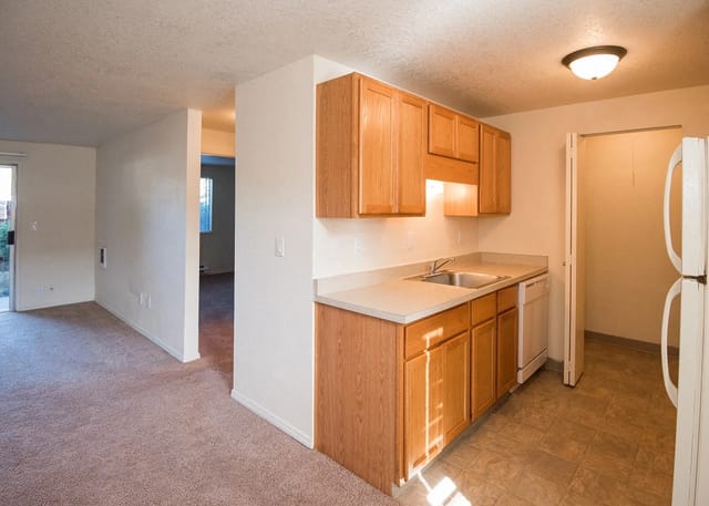 Kitchen area with light wood cabinets and white appliances