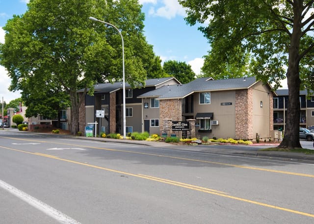 Exterior of Garden Glen Apartments building with trees and signage.