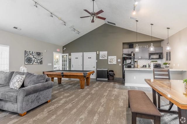 Interior of a community lounge with a pool table, sofa, and kitchenette.