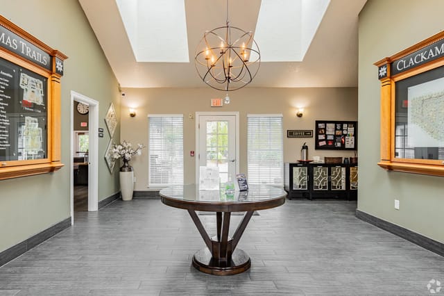 Interior apartment community lobby with a round glass table, chandelier, and coffee area.
