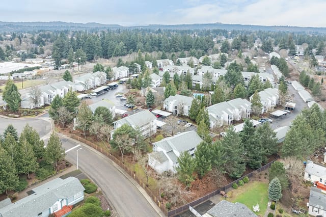 Aerial view of a suburban apartment community with many buildings, trees, and parking areas.