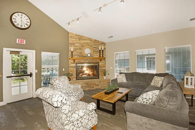 Clubhouse living area with a stone fireplace and comfortable seating.