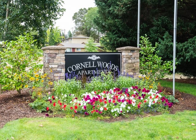 Cornell Woods Apartments monument sign with colorful flowers.