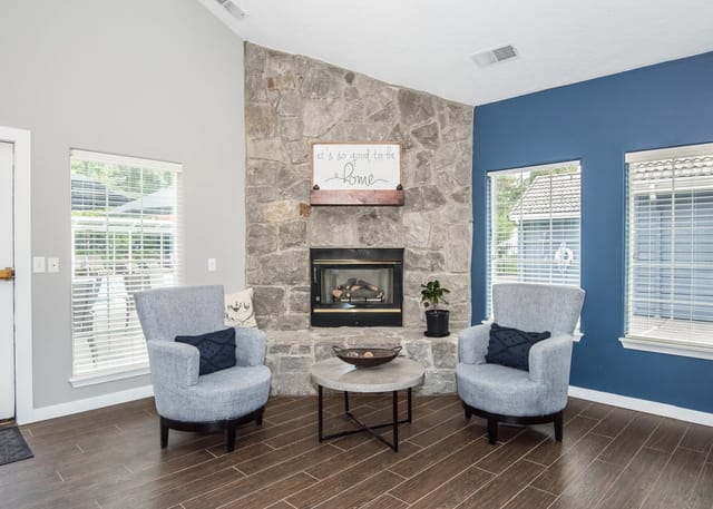 Living room with a stone fireplace, two armchairs, and a coffee table.