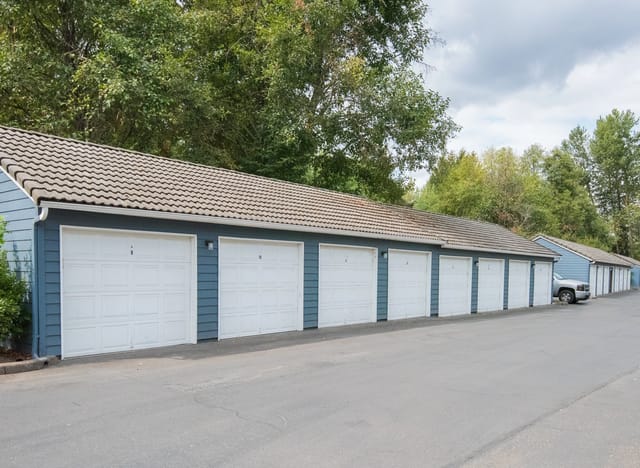 Row of garages with white doors and blue siding.