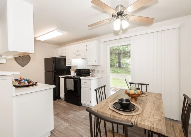 Kitchen and dining area with a table set for a meal, black appliances, and a ceiling fan.
