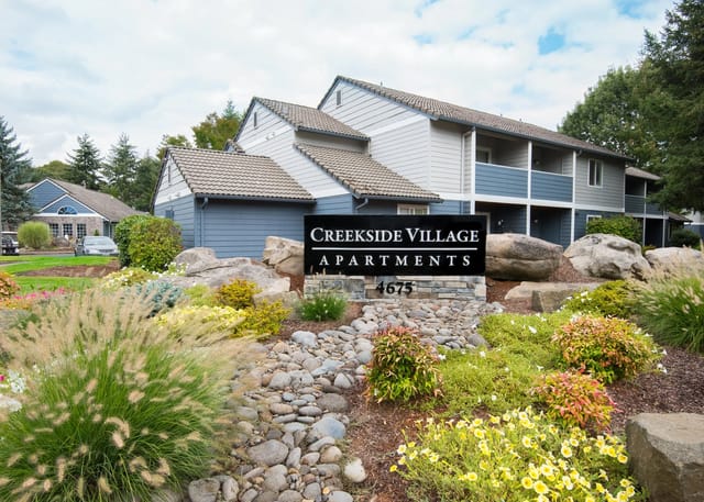 Creekside Village Apartments monument sign with landscaping and apartment buildings in background.