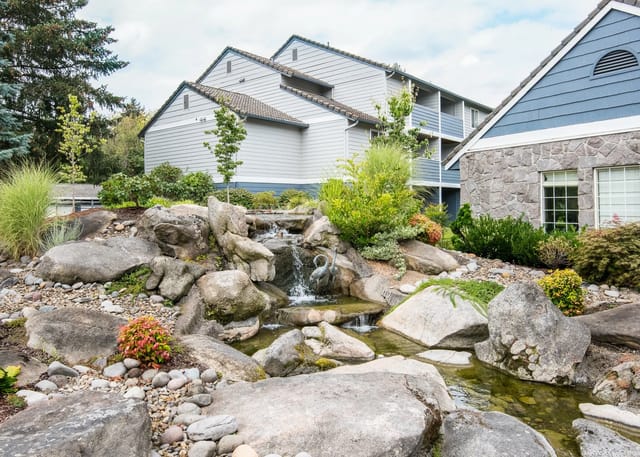 Apartment complex exterior with a decorative waterfall and landscaping.
