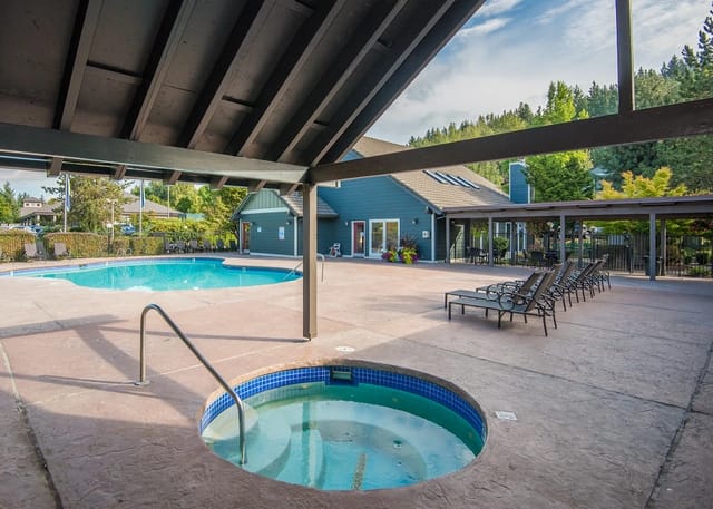 Outdoor swimming pool and spa area with lounge chairs and covered seating.