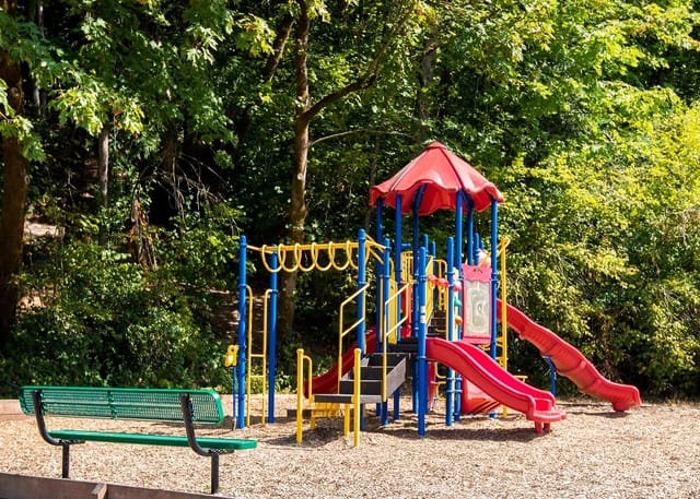 Playground with slides, swings, and a bench.