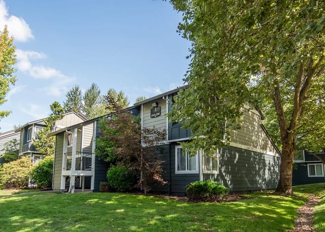 Exterior view of apartment buildings with lush green lawns and trees.