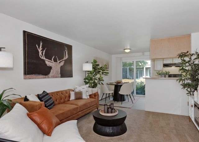 Modern living room with a tan sofa, coffee table, and a large abstract deer painting on the wall.