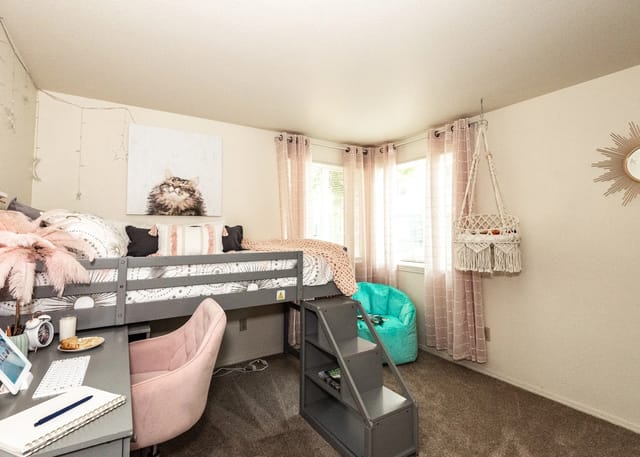 Stylish loft bed with a desk and chair in a well-decorated bedroom.