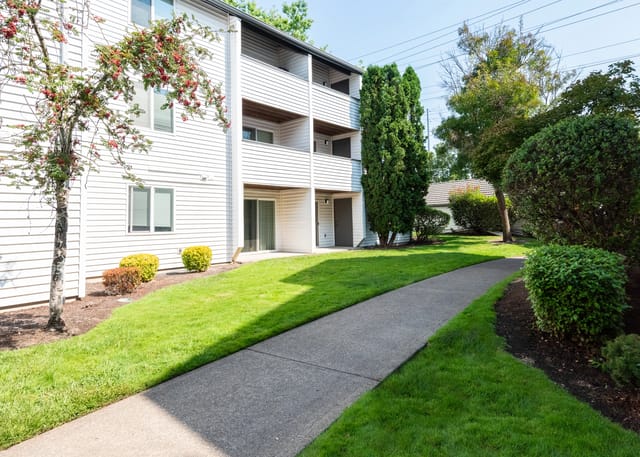 Exterior view of apartment building with pathway and landscaping.