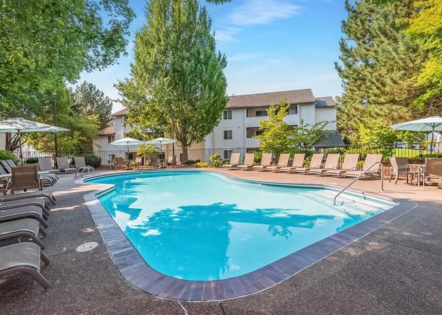 Outdoor swimming pool with lounge chairs and umbrellas.