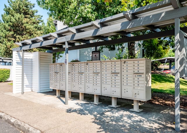 Mailboxes under a gray pergola on a sunny day.