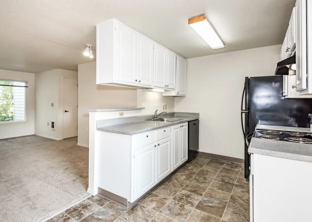 Kitchen area with white cabinets, granite countertops, stainless steel sink, and black appliances.