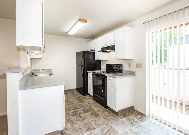 Kitchen with white cabinets, black appliances, and a sliding glass door.