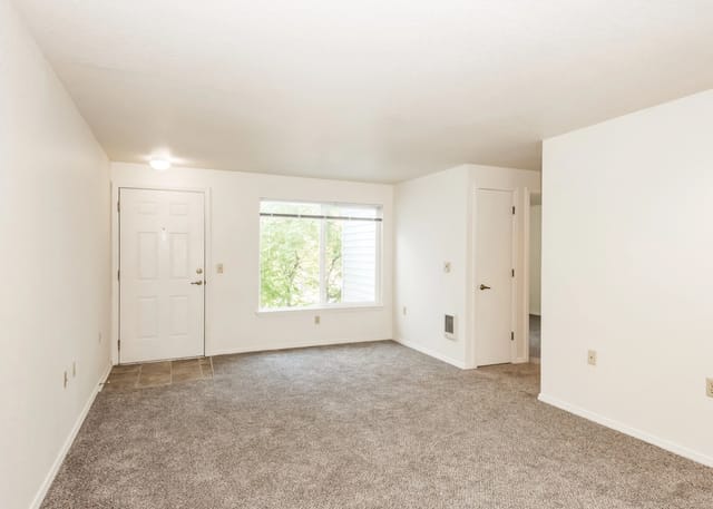 Interior view of an apartment living room with a white door and a large window
