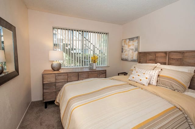 Bedroom with a queen-size bed, dresser, and mirror.