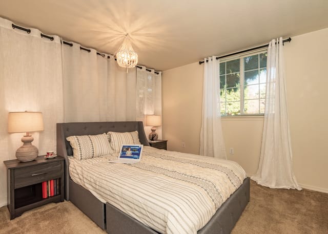 Bedroom with a queen-size bed, nightstands, and a chandelier.