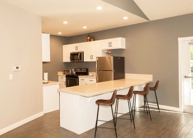 Kitchen with white cabinets, stainless steel appliances, and a breakfast bar with bar stools.