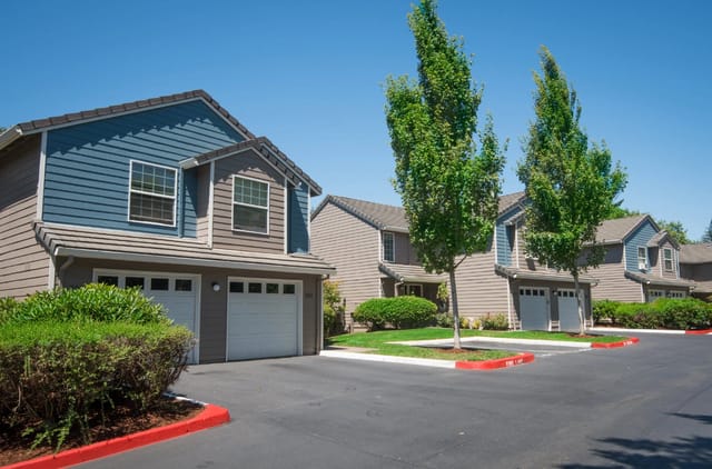 Exterior view of townhouses with garages and manicured landscaping.