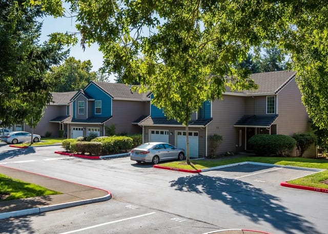 Exterior view of apartment buildings with garages and parking lot.