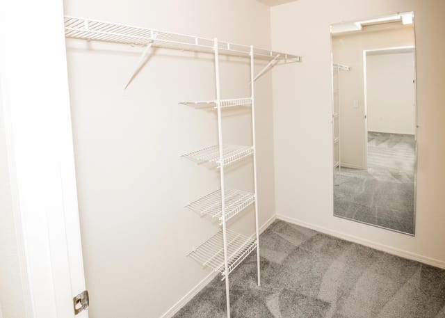 Closet with wire shelving and a full-length mirror.