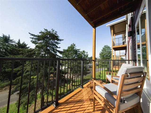 Balcony with seating overlooking trees and adjacent units.